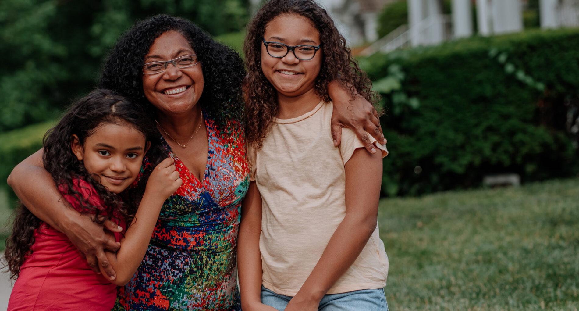 Smiling woman with two young girls outdoors.