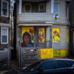 House with colorful mural and parked car.