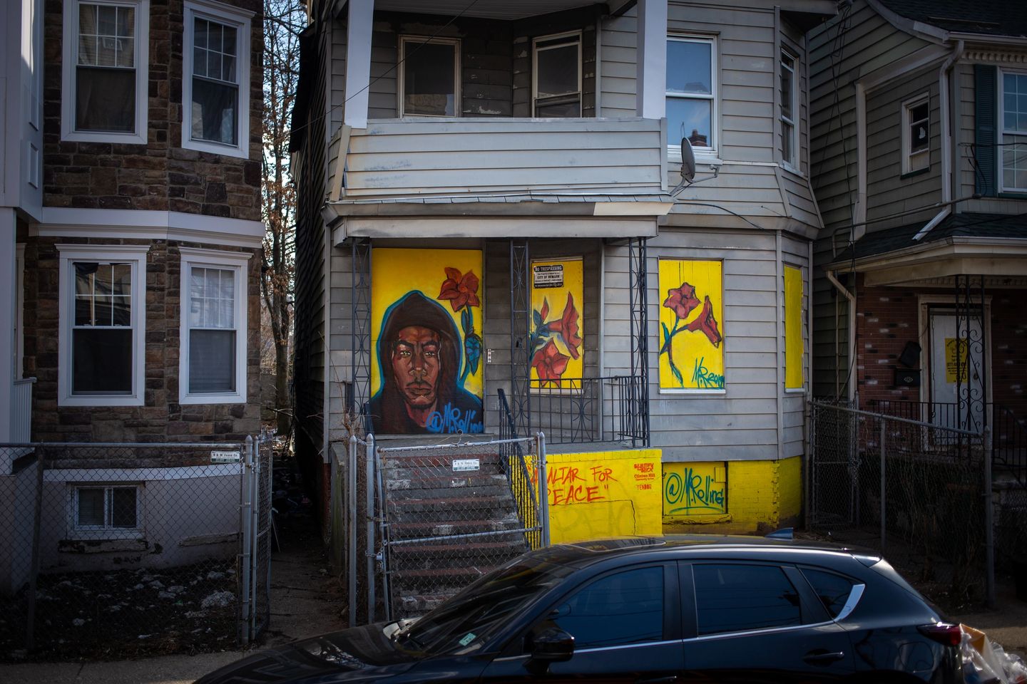House with colorful mural and parked car.