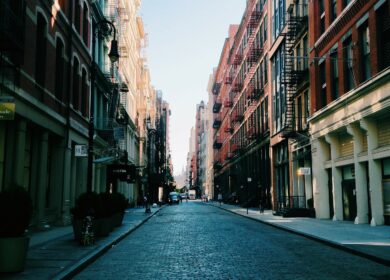 A street with many buildings and some people walking on it