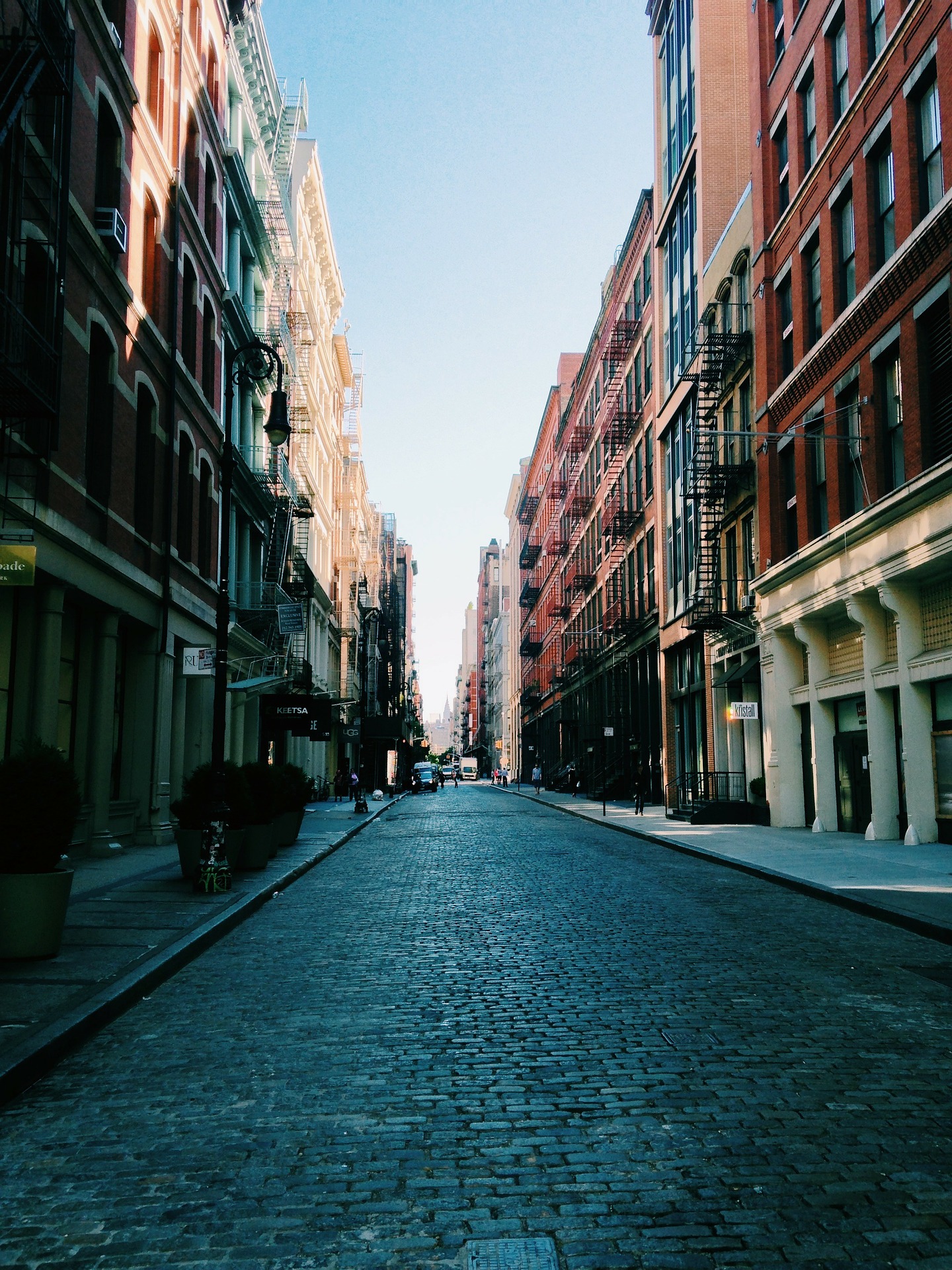 A street with many buildings and some people walking on it