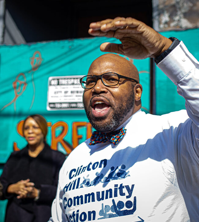Man speaking in front of colorful mural.