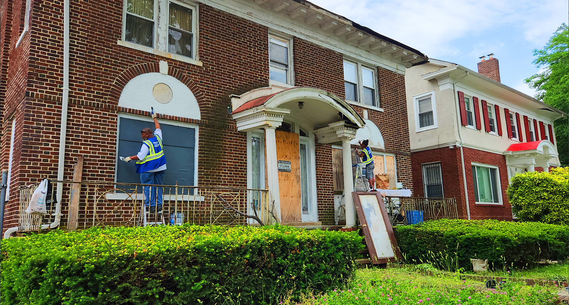 Workers repairing brick house exterior facade.